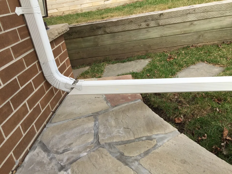 Downspout extension directing roof water away from the home