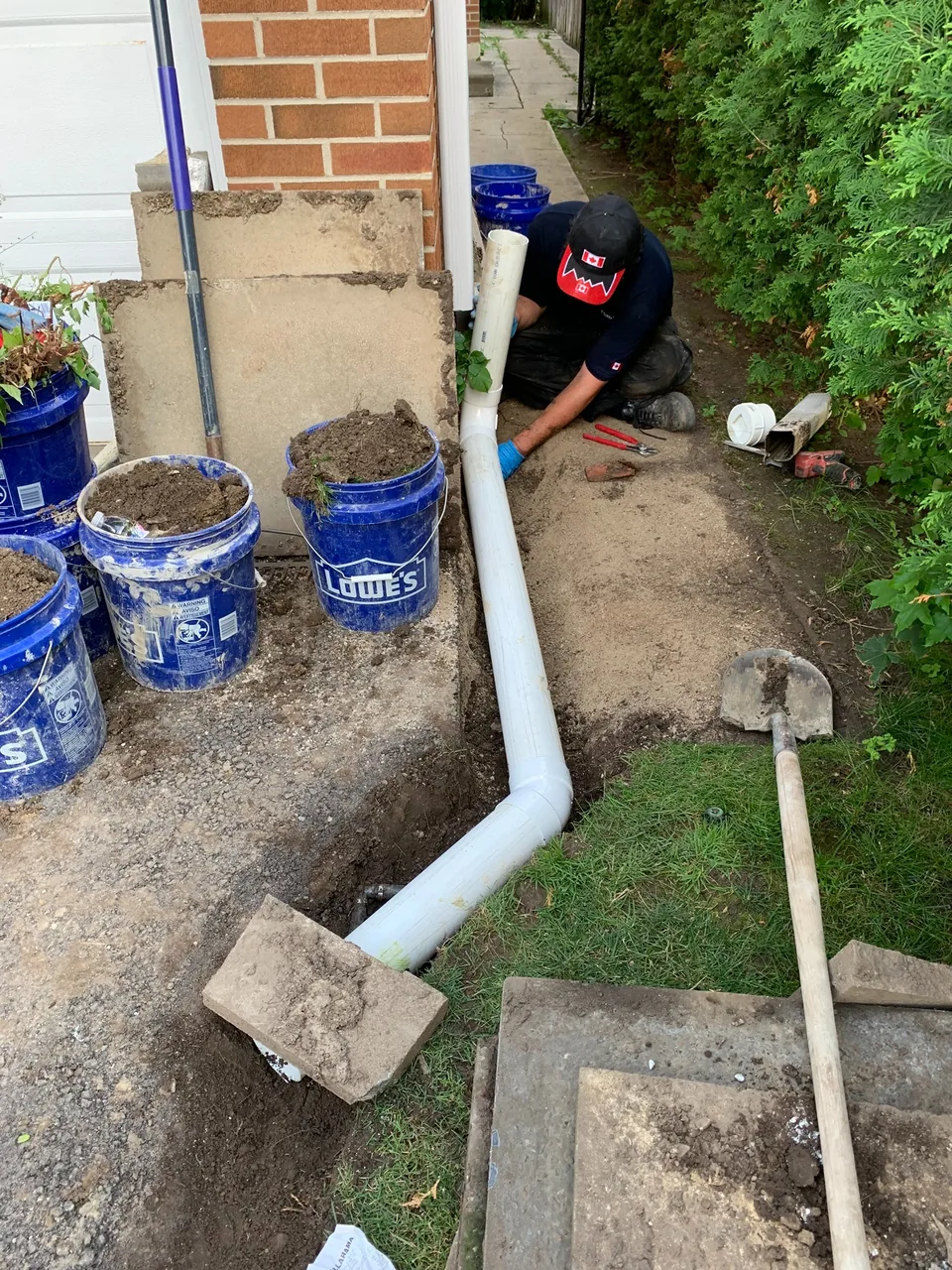 Technician completing a downspout drainage installation