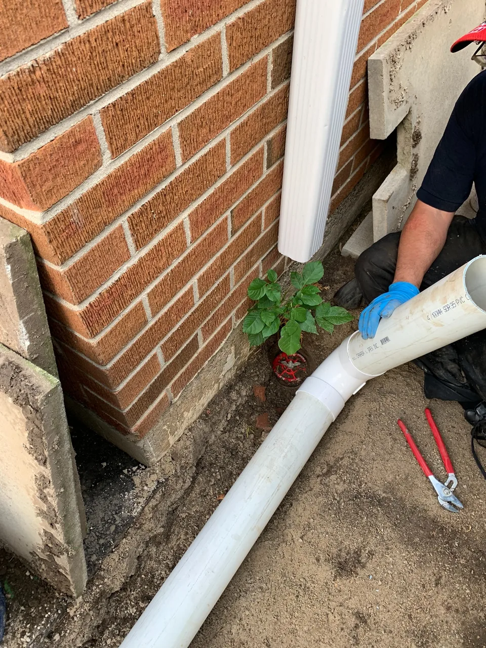 Large drainage pipe being connected beside a brick Toronto-area home